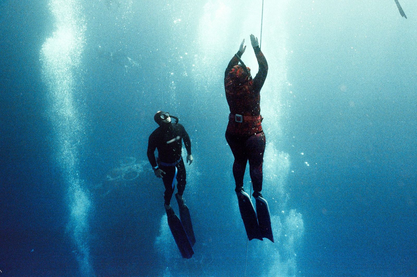 Two freedivers rising toward the light