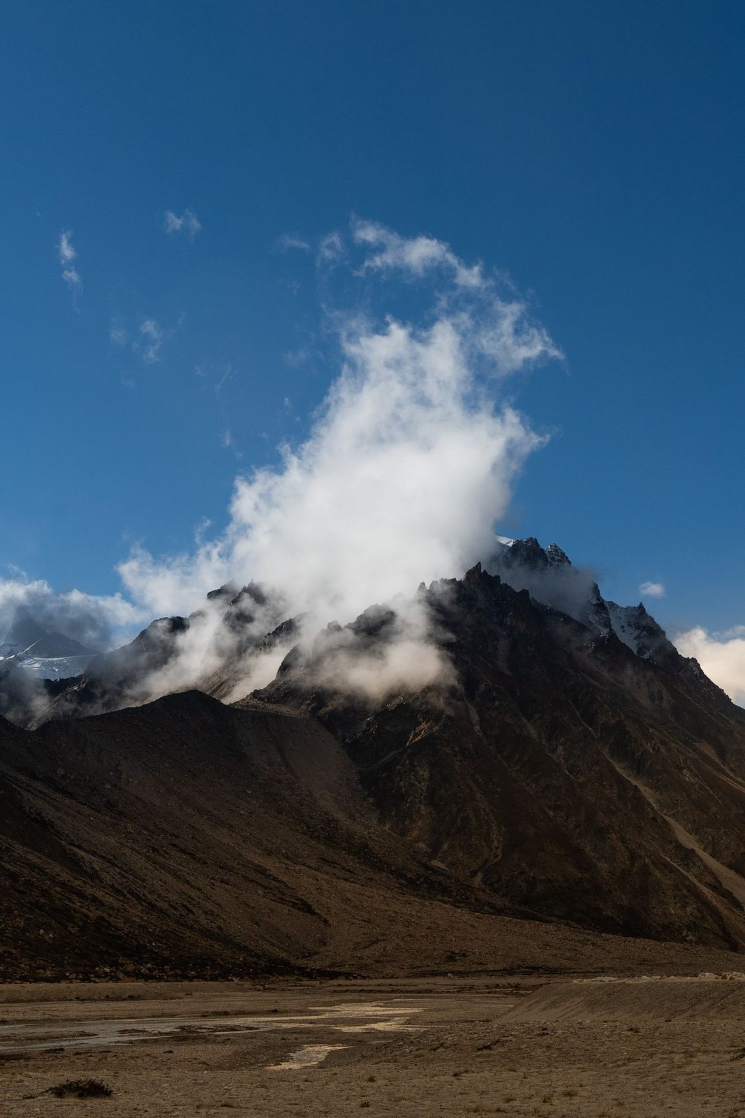 Dark peak with a cloud breaking over it