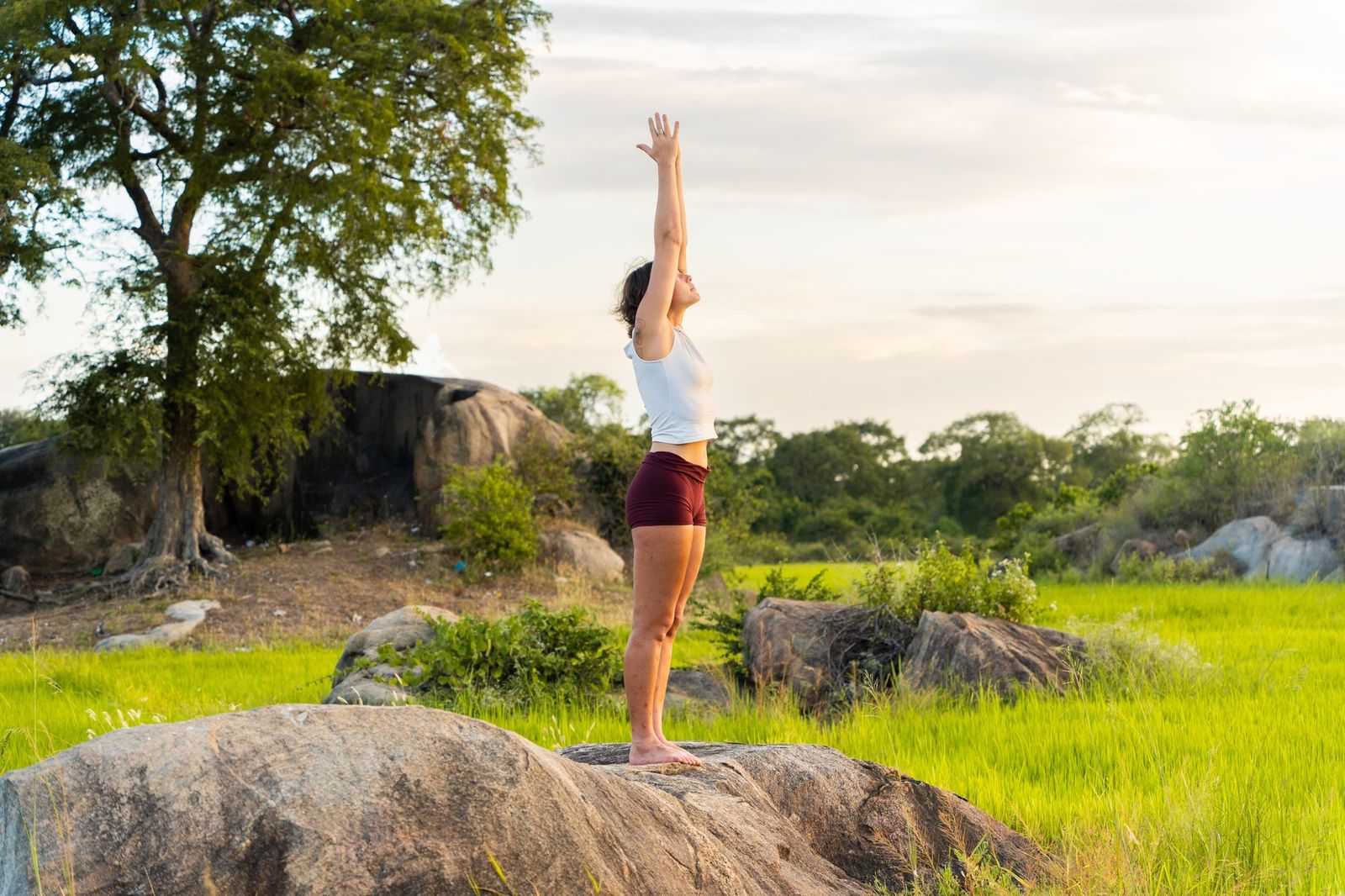 Standing yoga pose on a boulder at golden hour