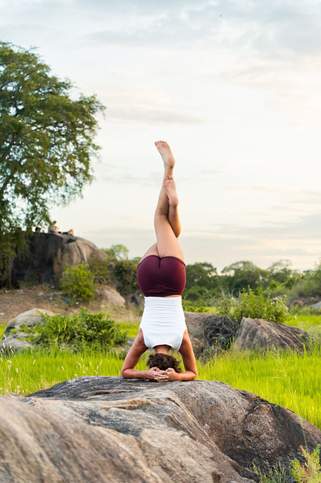 Headstand on a boulder in a green field