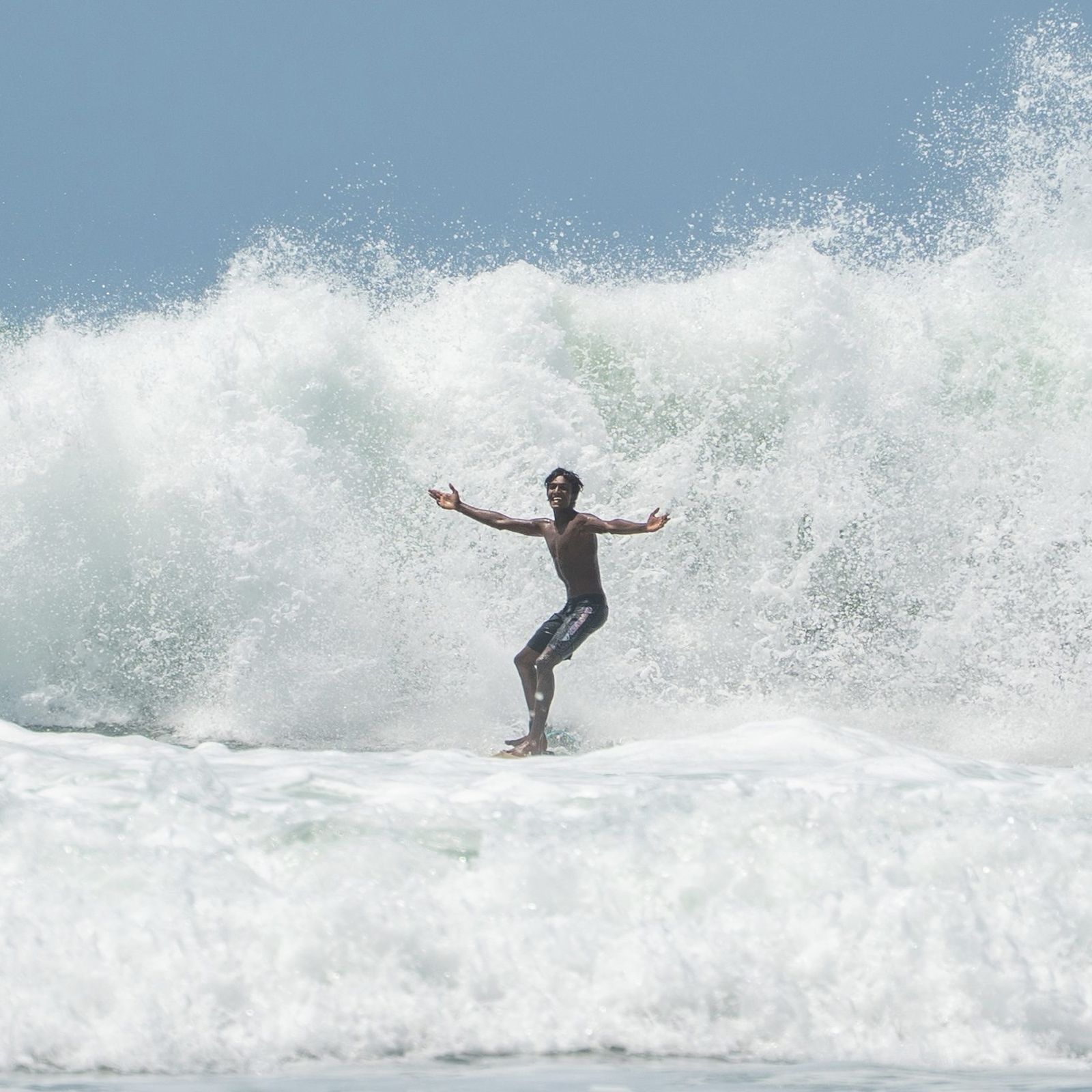Surfer with arms spread wide in front of exploding whitewater